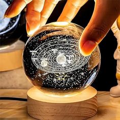 a person touching the top of a crystal ball on a wooden stand with other items in the background