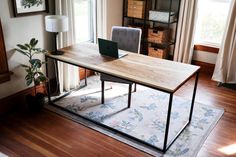 a wooden table with a laptop on top of it in front of a large window