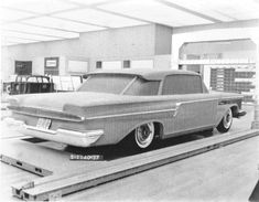 an old black and white photo of a car being worked on in a factory or repair shop