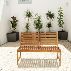 two wooden benches sitting next to each other in front of potted plants on the side of a building