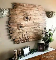 a wooden wall hanging on the side of a table with pictures and flowers in vases