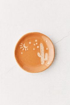 a small ceramic plate with a cactus design on the front and side, sitting on a white surface