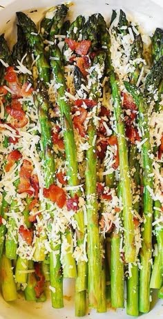 asparagus with parmesan cheese and bacon on top in a white dish