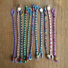 several different colored ropes on a wooden surface with beads and bells attached to them,