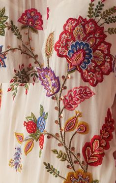 a close up view of a white dress with colorful flowers and leaves on the back