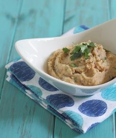 a white bowl filled with mashed potatoes on top of a blue and white napkin