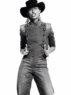 a black and white photo of a woman wearing a cowboy hat with her hands in her pockets