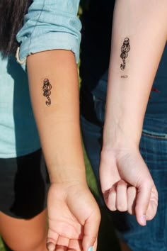 two people holding hands with small tattoos on their arms and wrist, both showing the same tattoo design