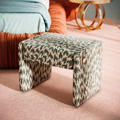 a foot stool sitting on top of a pink carpeted floor next to a bed