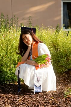 a woman sitting on the ground with flowers in her hand