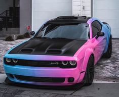 a pink and blue car parked in front of a building