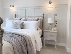 a bed with white linens and pillows in a small room next to a night stand