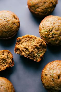 several muffins on a blue surface with one cut in half to show the inside