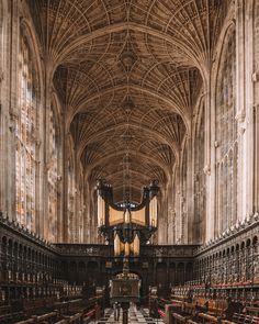 the interior of a large cathedral with vaulted ceilings and wooden pews on either side