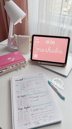 a desk with a notebook, calculator and pen on it in front of a window