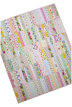 a quilt made with strips and flowers on the front, in pastel colors that are multicolored