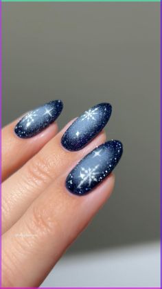 a woman's hand with blue and white nail polish on her nails, decorated with snowflakes