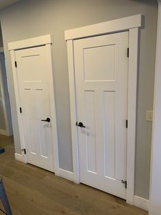 three white doors in a room with hard wood flooring