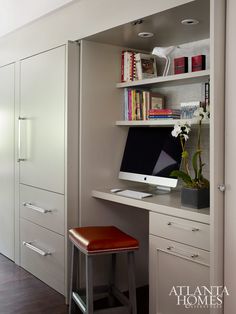 a desk with a computer on top of it next to a book shelf and drawers