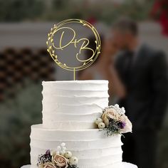 a wedding cake with a monogrammed initials on top and flowers in the middle