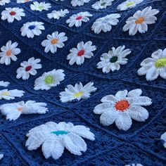 a crocheted blanket with white daisies on it