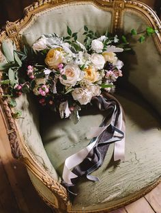 a bouquet of flowers sitting on top of a green chair next to a black and white ribbon