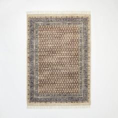 an area rug with fringes on the floor in front of a white wall,