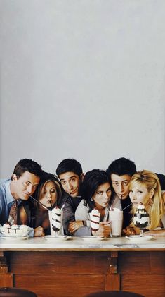 a group of people sitting at a table with cakes and drinks in front of them