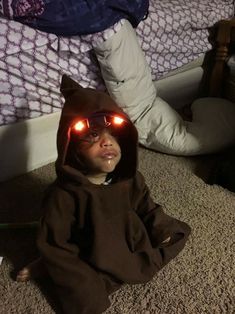 a little boy wearing red glasses sitting on the floor