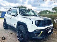 a white jeep parked on top of a gravel road