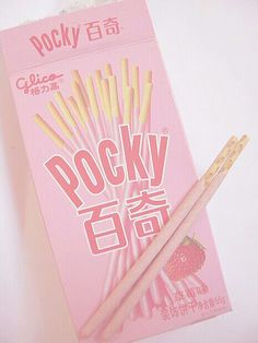 a package of rock candy sticks sitting on top of a white table next to a pair of chopsticks