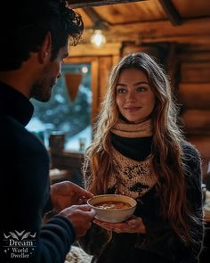 a woman holding a bowl of food while standing next to a man in a black sweater