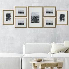 a living room with white couches and pictures on the wall above them, along with a coffee table