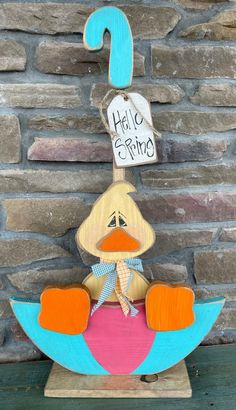 a wooden duck sitting on top of an umbrella with a sign that says hello spring