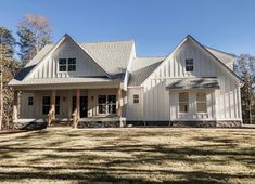 a large white house sitting on top of a grass covered field with trees in the background