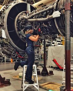 a woman is working on an airplane engine