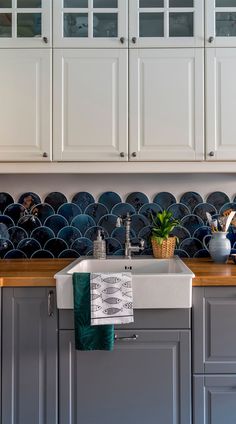 a kitchen with white cabinets and blue backsplash