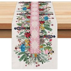 the table runner is decorated with colorful flowers and leaves on white linen, along with pink ribbon