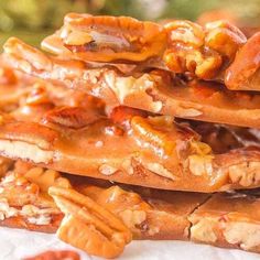 a stack of pecan brittles sitting on top of a white paper towel covered in nuts