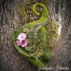 a mossy tree with a pink flower on it's head and an animal figure in the trunk