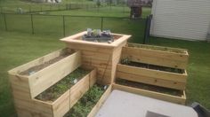 several wooden raised planters with plants growing in them on the side of a yard