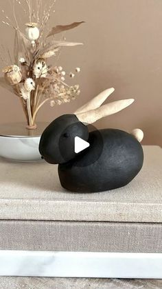 a black bird statue sitting on top of a table next to a bowl with flowers in it