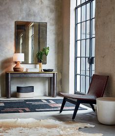 a living room with a chair, mirror and rug on the floor in front of an open window