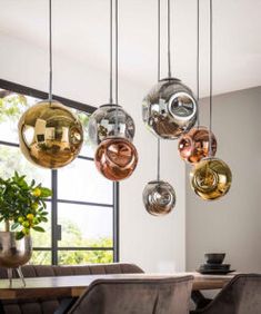 a dining room table with chairs and hanging glass orbs over it's head