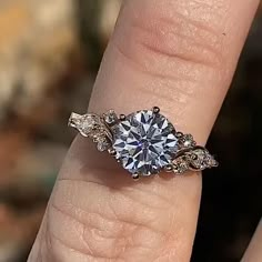 a woman's hand with a diamond ring on top of her finger and an engagement band