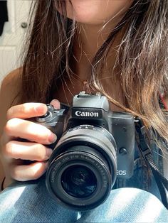 a woman taking a photo with her canon eos camera in front of her face