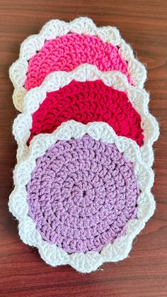 three crocheted dishcloths sitting on top of a wooden table