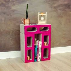 a pink shelf with books and a potted plant on top