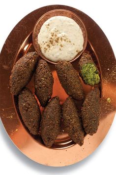 a copper plate topped with falafes covered in sauce