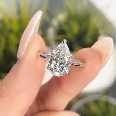 a woman's hand holding a ring with a large diamond in the middle of it